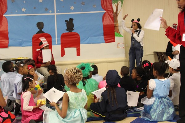 1st grade students settle in to hear seventh grade student, Clare read, "Cat in the Hat" for Literacy Fun Day.